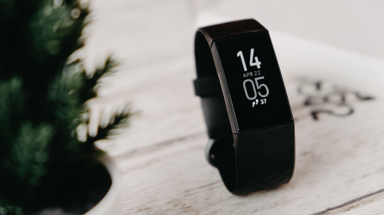 The Fitbit Charge 4 on a table beside a plant.