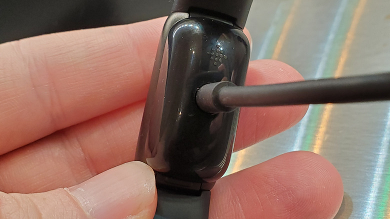 The back of the Fitbit Luxe on its charger.
