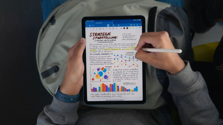 Hands holding iPad while highlighting a note with Apple Pencil