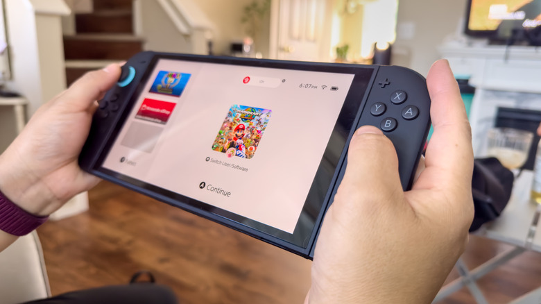 a person holding the Nintendo Switch 2 undocked showing the default Nintendo software