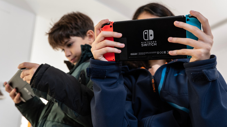 Two Nintendo Switch consoles with two people holding it