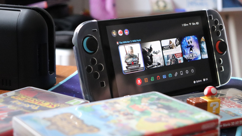 A pile of games sitting next to a Nintendo Switch 2 turned on showing battery bar in top right of the screen