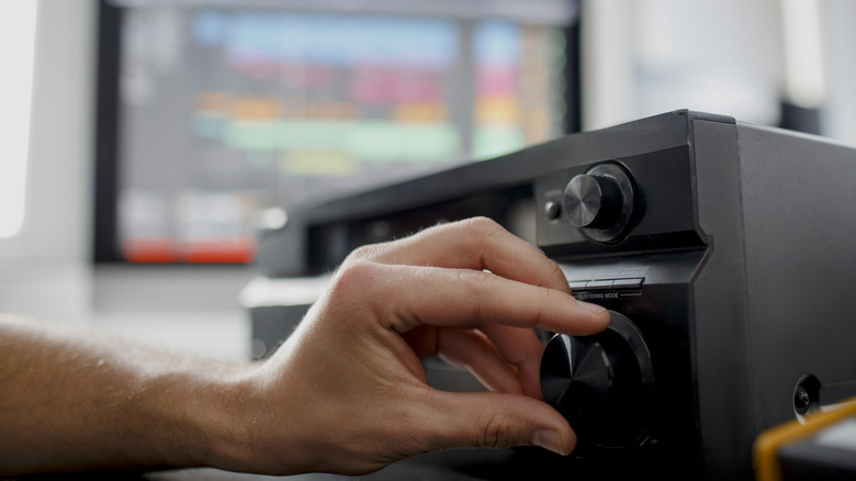 A person manually adjusting settings for an AV receiver.