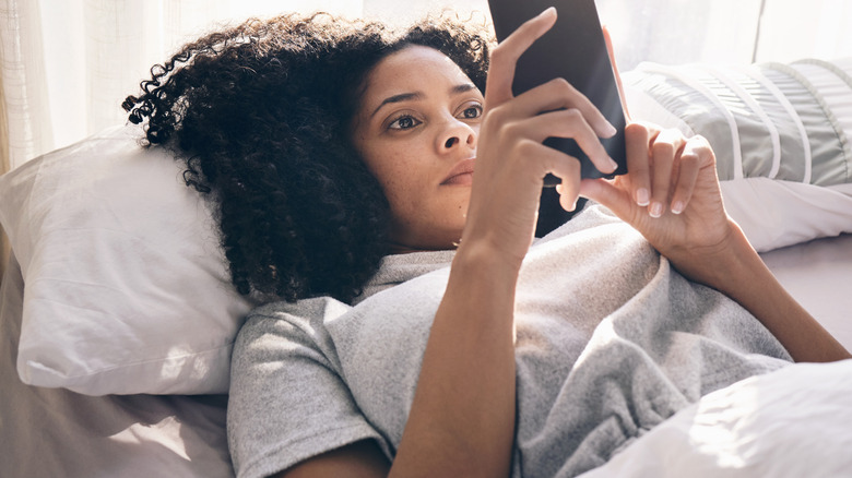 Woman in bed scrolling through phone