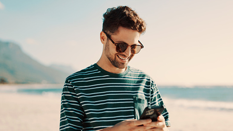 Person checking iPhone at beach