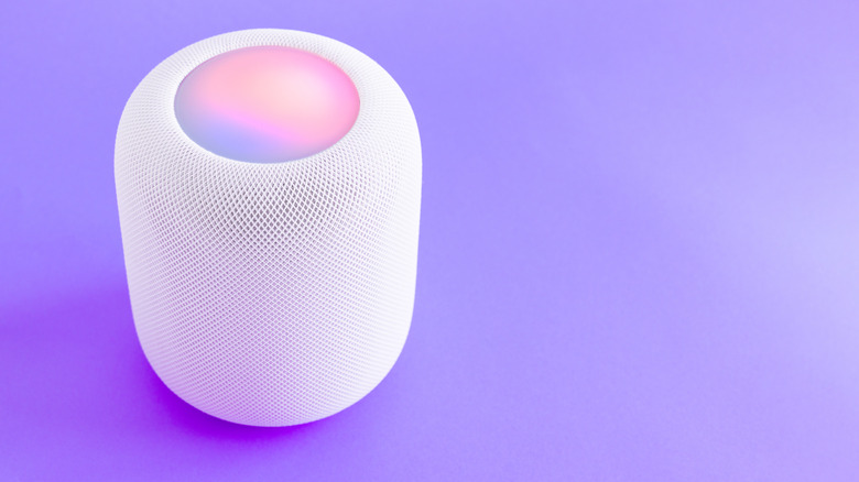 A white Apple HomePod set against a purple backdrop.