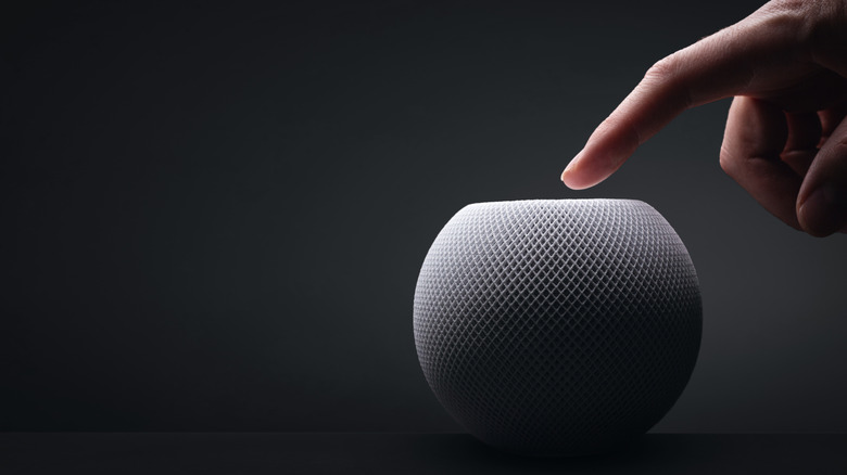 A person interacting with a white Apple HomePod mini.