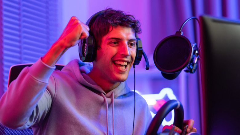 A young male streaming a driving game with  a gaming headset and USB microphone with a pop filter