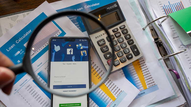 OnePlus smartphone with Facebook app  on top of paper and calculator