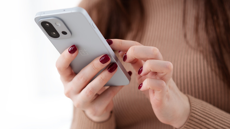 Person holding OnePlus 13S or 13T smartphone