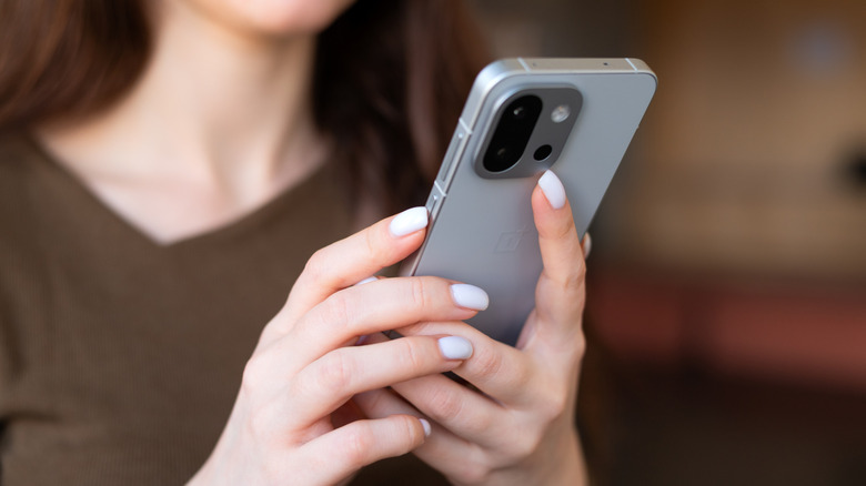 Woman holding OnePlus 13S or 13T smartphone