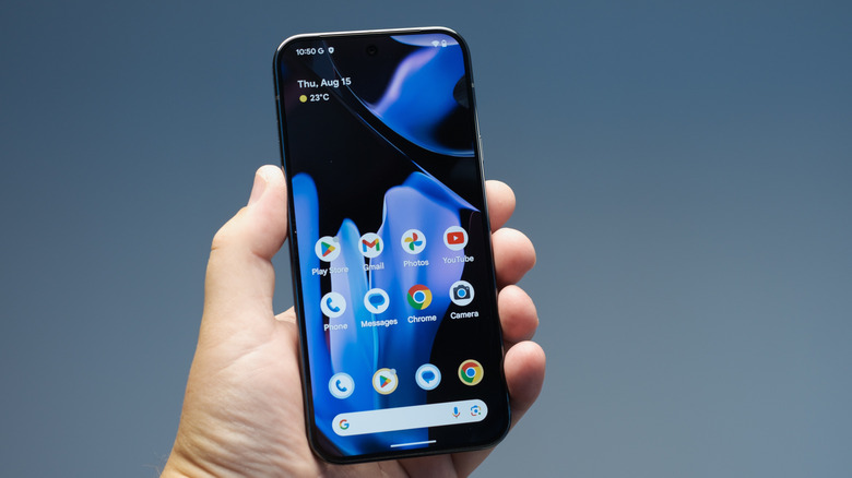 Person holding up a Pixel 9 phone showing the home screen