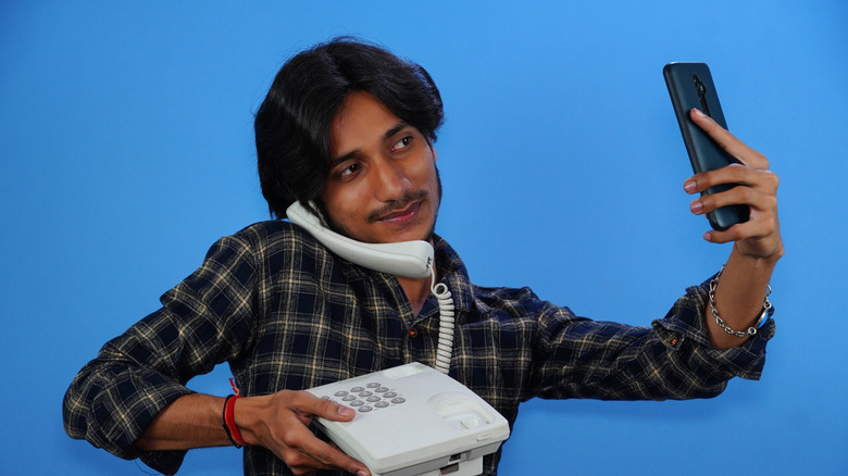 Person holding an landline phone and then a smartphone in one hand