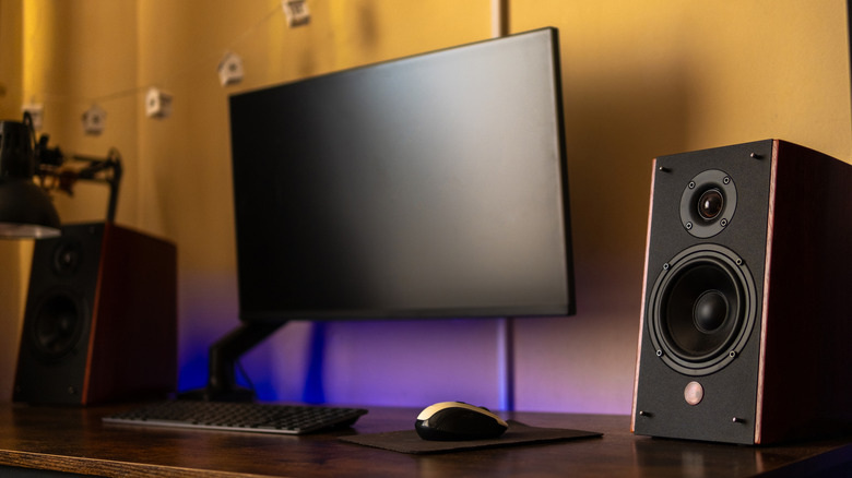 A computer desktop with a large monitor and speakers