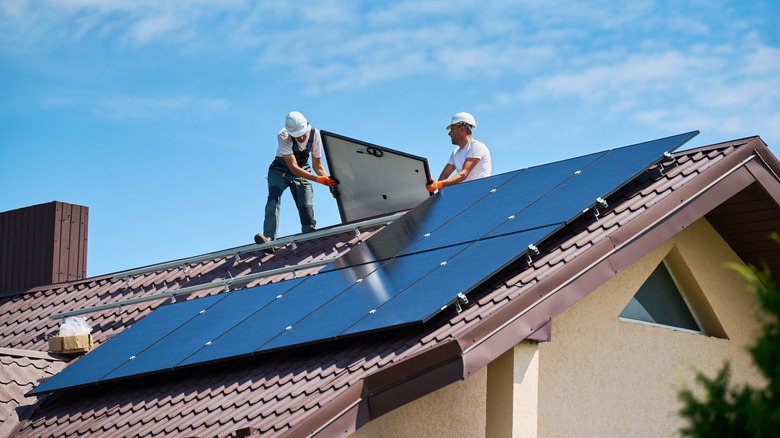 Two men install a solar panel system on a roof