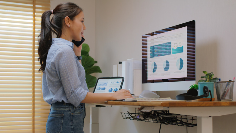 woman using a standing desk and looking at her computer monitor