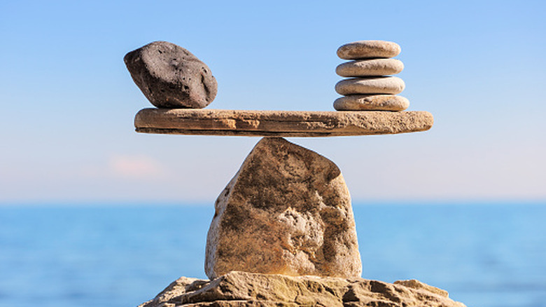 stone scale, concept of balance, ocean visible in the background (blurred)