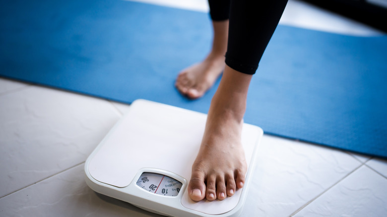 person stepping onto a scale, concept of burning calories/losing weight