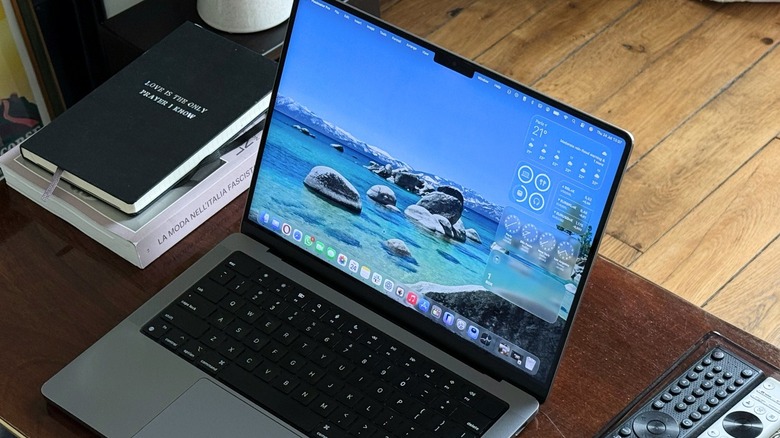 Close-up shot of an opened MacBook Pro on a desk with a few notebooks and remote controls around