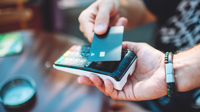 Person using a contactless credit card on a payment terminal.