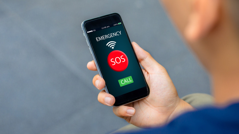 person holding a smartphone with the screen showing Emergency SOS Call