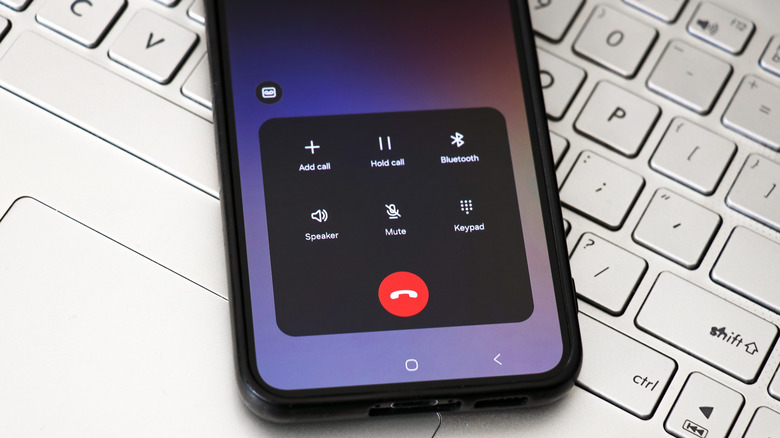 smart phone with an active call placed on a laptop's keyboard