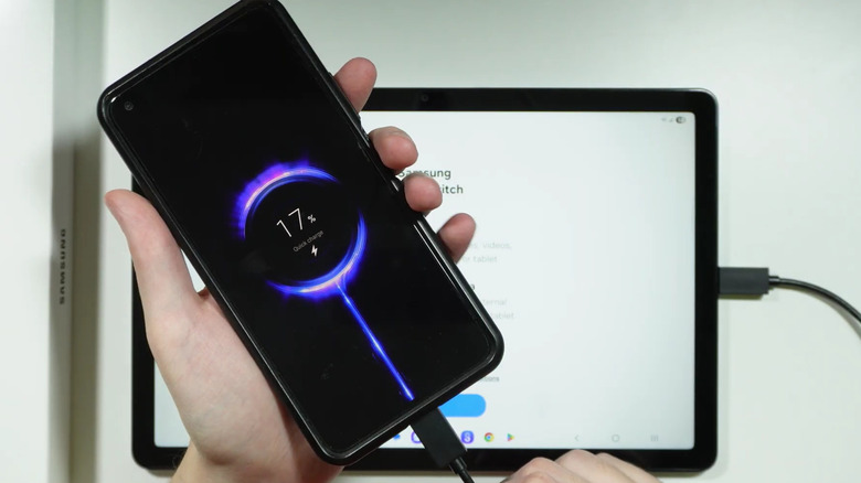 A Samsung smartphone being charged with a Samung Galaxy tablet, with a USB-C cable connecting the two devices