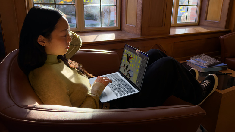 A woman sitting in a chair using a MacBook air