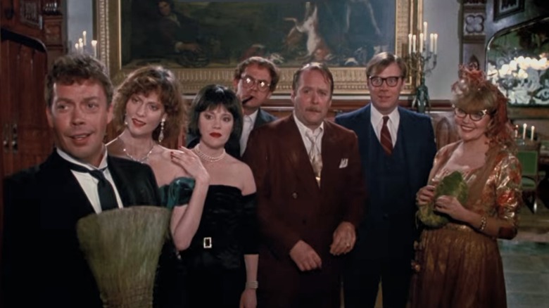 The cast of Clue with Tim Curry in front holding a broom