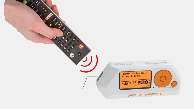 Hand pointing TV remote at Flipper Zero