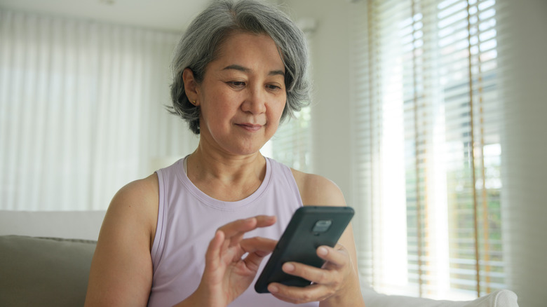 a woman with grey hair scrolling on her phone