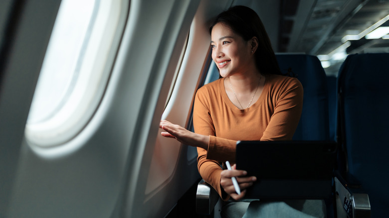 A woman looking out the window of an airplane.