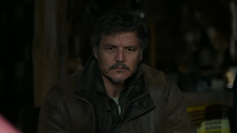 Joel Miller sitting indoors with a tense expression in The Last of Us.