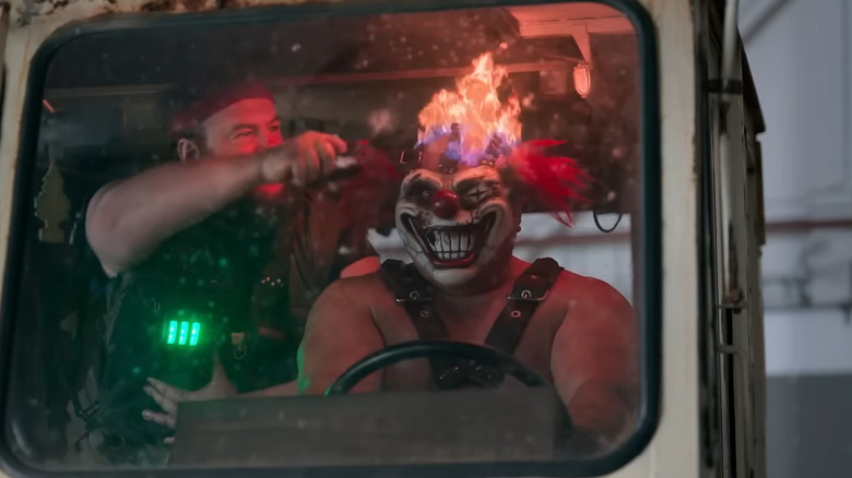 Sweet Tooth driving his truck with his flaming clown head while Stu rides beside him in Twisted Metal.