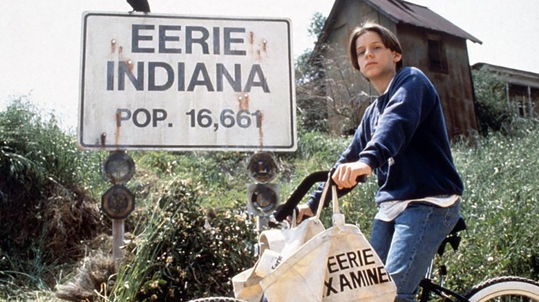 A boy riding his bike by a sign that reads Eerie, Indiana.