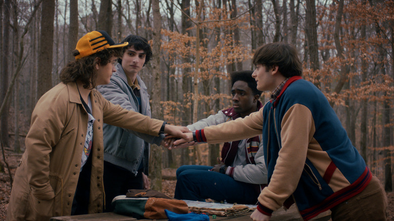 Gaten Matarazzo, Finn Wolfhard, Caleb McLaughlin, and Noah Schnapp around a table in Stranger Things.