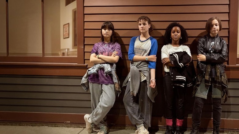 Four kids leaning against the side of a building in Paper Girls.