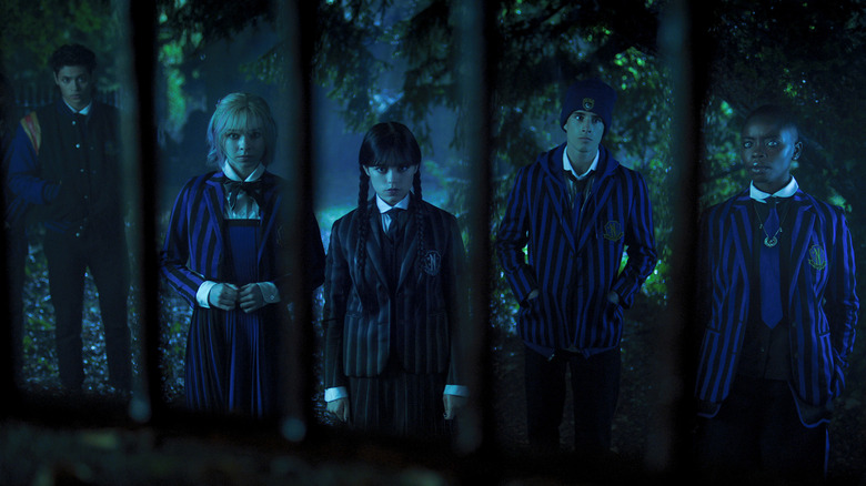 Wednesday standing with other Nevermore students in the forest.