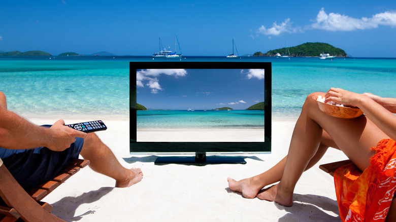 Couple watching a TV on a beach