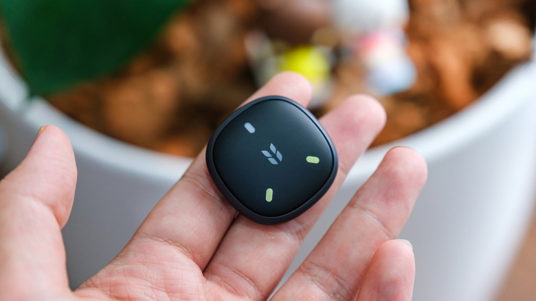 A black Ugreen FineTrack Mini 2 tracker resting in a person's open palm.