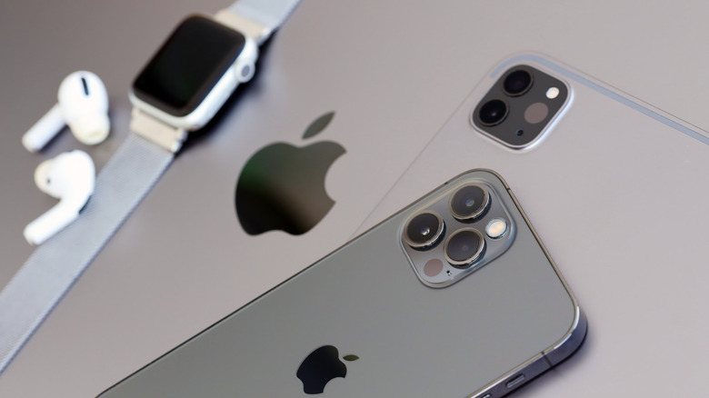 an iPhone, iPad, Apple Watch and AirPods placed on a MacBook