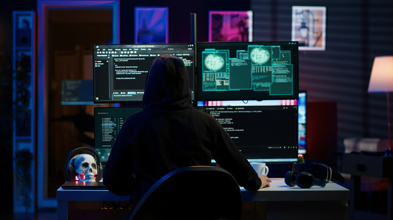 A hacker seated at a bank of computer monitors.