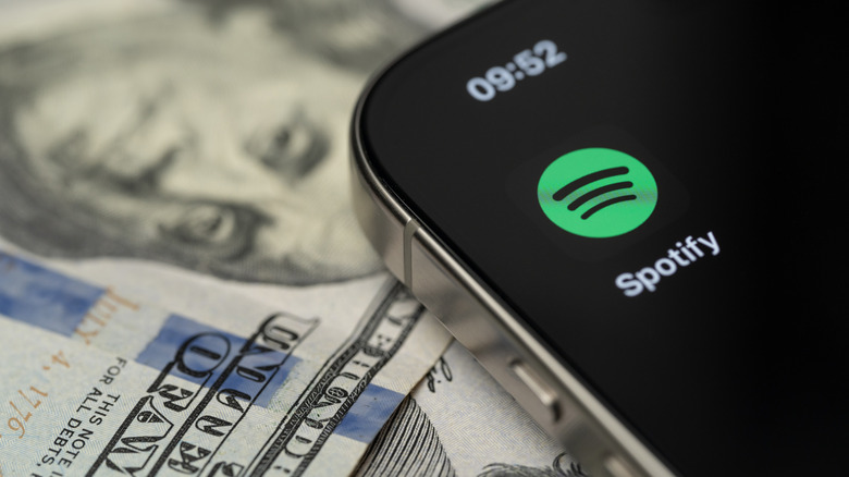 Smartphone with Spotify app displayed placed on US dollar bill