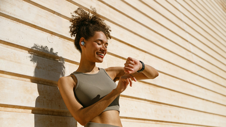 Young fit woman looking at smartwatch and counting calories burned.