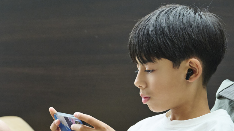 Boy playing a mobile game with earbuds