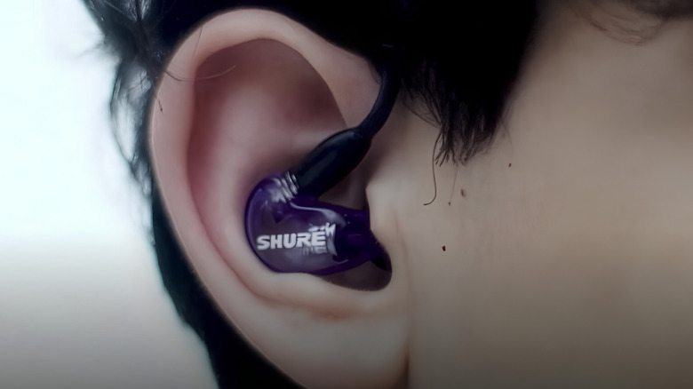 A person wearing Shure SE215 PRO Sound Isolating Wired Earbuds