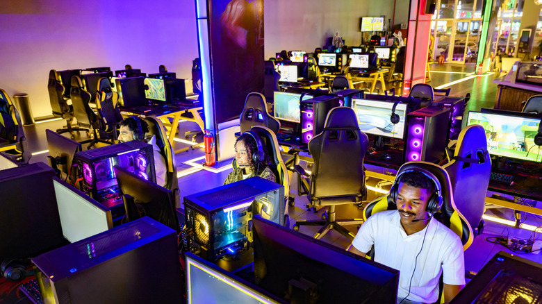 A man and woman playing games on PCs via a gaming monitor.