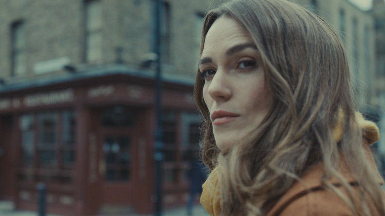 Kiera Knightley as Helen Webb stood outside a shop in Black Doves