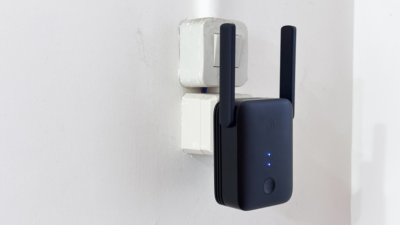 a black wi-fi range extender plugged into a power socket