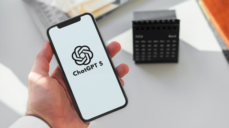 A hand holding a smartphon with the OpenAI logo on the screen and the words ChatGPT-5.